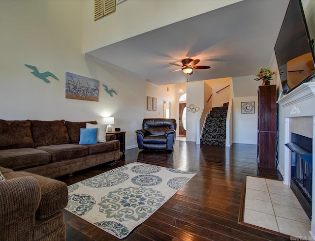 living room with a fireplace, wood finished floors, visible vents, a ceiling fan, and stairs