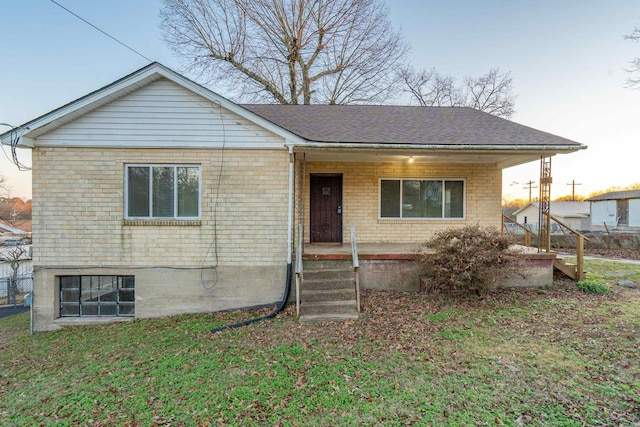 view of front of home featuring roof with shingles, brick siding, and a front lawn