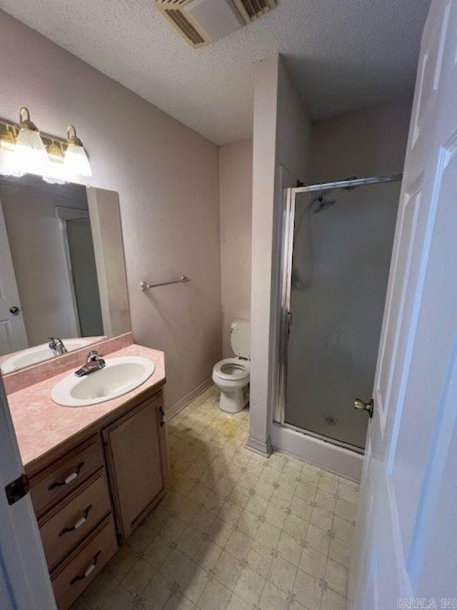 full bath featuring a stall shower, toilet, tile patterned floors, a textured ceiling, and vanity