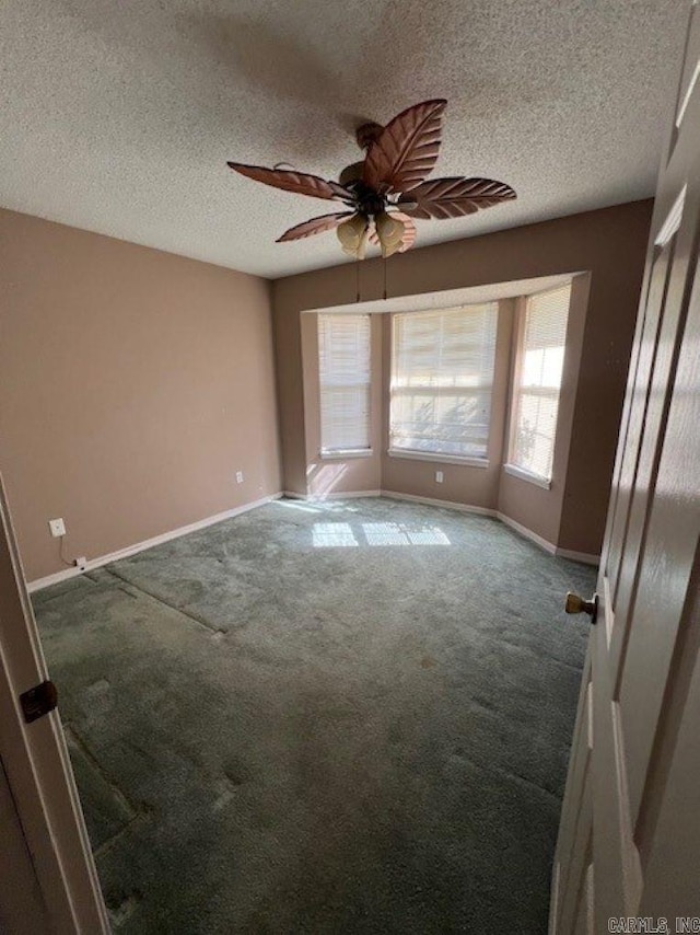 carpeted spare room featuring ceiling fan, a textured ceiling, and baseboards