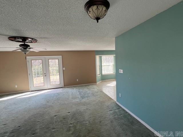 spare room with carpet floors, baseboards, a textured ceiling, and french doors