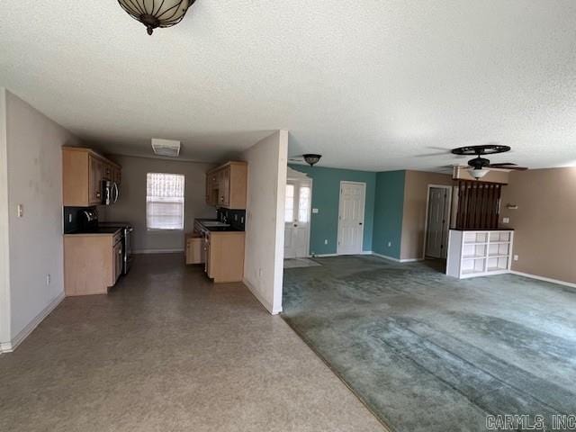 kitchen featuring a ceiling fan, plenty of natural light, stainless steel microwave, and a textured ceiling