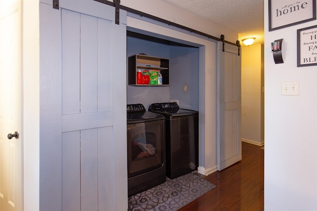 clothes washing area featuring a textured ceiling, a barn door, laundry area, separate washer and dryer, and dark wood-style floors