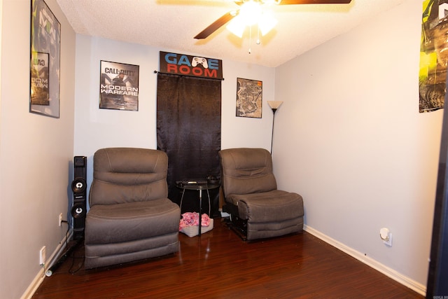 living area with ceiling fan, a textured ceiling, baseboards, and wood finished floors