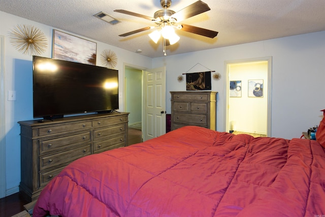 bedroom featuring a textured ceiling, a ceiling fan, visible vents, and ensuite bathroom