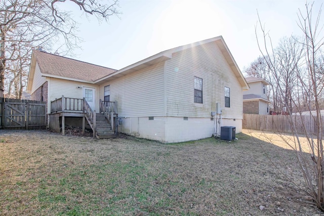 back of house with crawl space, a fenced backyard, a lawn, and stairway