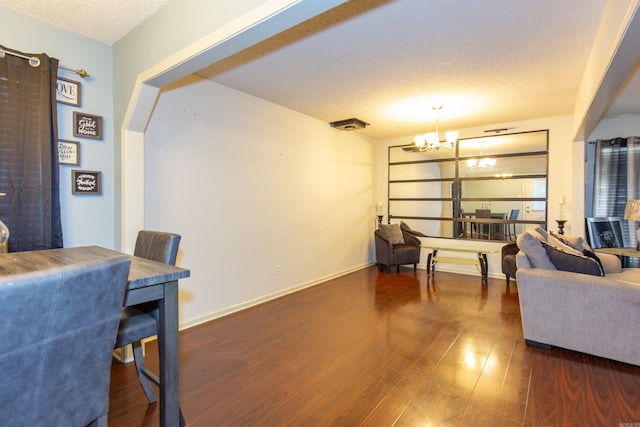 living room featuring wood finished floors, a textured ceiling, baseboards, and an inviting chandelier