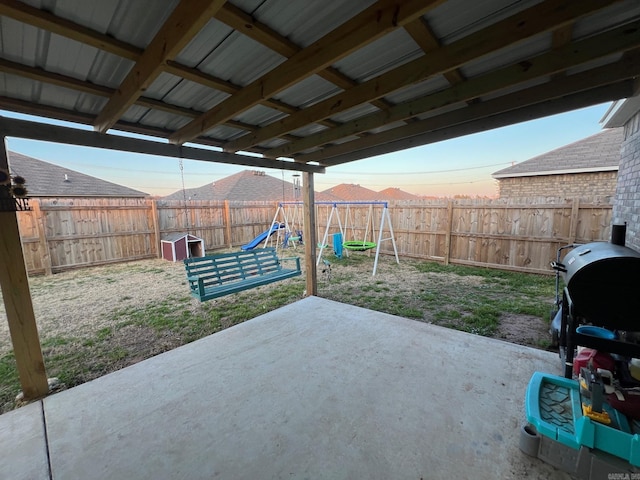 patio terrace at dusk with a fenced backyard and a playground