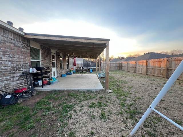 yard at dusk featuring a patio area and a fenced backyard