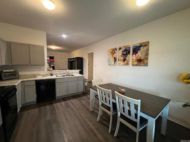 kitchen featuring dark wood-style floors, light countertops, gray cabinetry, a sink, and black appliances