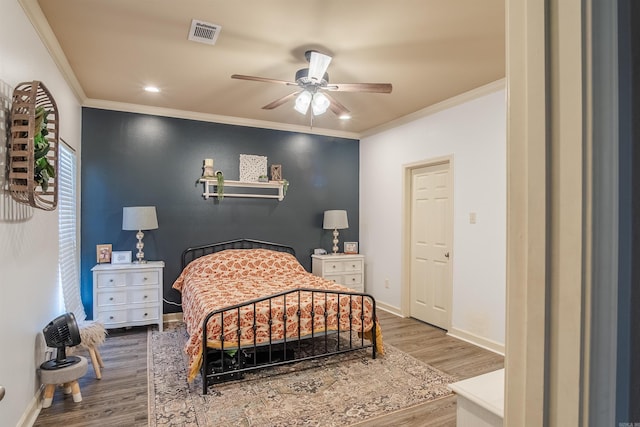 bedroom featuring ornamental molding, wood finished floors, visible vents, and baseboards