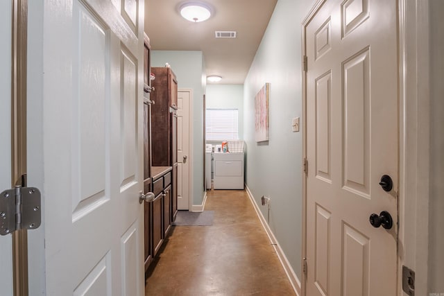 corridor with finished concrete floors, washing machine and dryer, visible vents, and baseboards