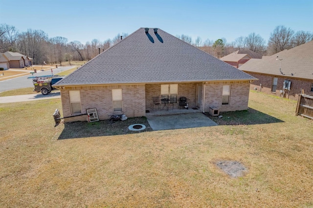 back of property featuring a patio, a yard, a shingled roof, and brick siding