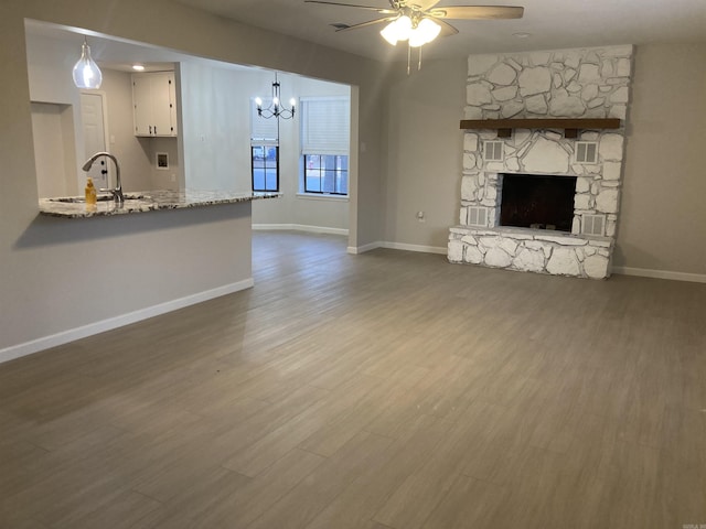 unfurnished living room with wood finished floors, a sink, a ceiling fan, and baseboards