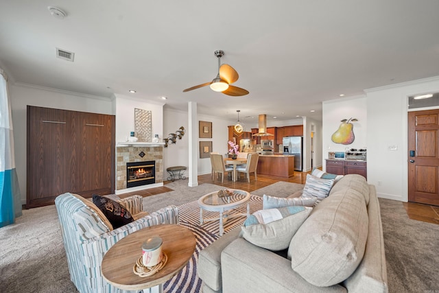 living room with baseboards, visible vents, a tiled fireplace, ornamental molding, and recessed lighting