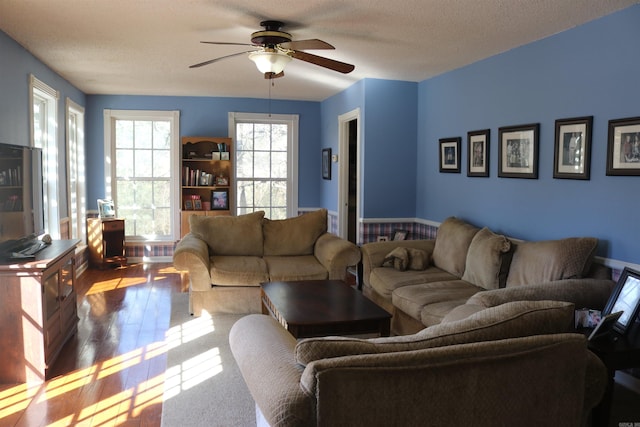 living area with ceiling fan, a textured ceiling, and wood finished floors