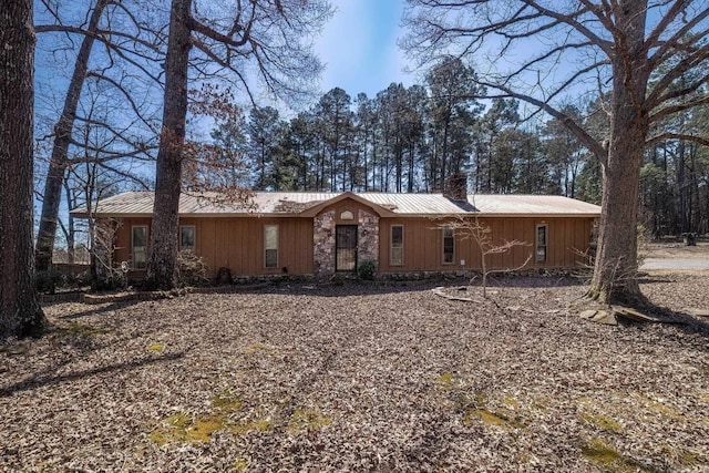 view of front of home with stone siding, a chimney, metal roof, and a standing seam roof