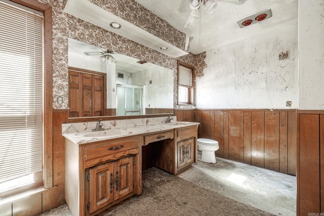 bathroom featuring double vanity, ceiling fan, a sink, and wainscoting