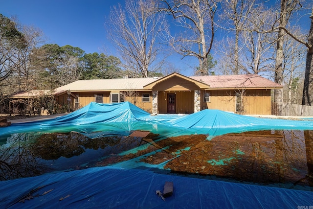 view of front of house featuring stone siding and fence