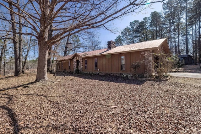 view of property exterior featuring board and batten siding, metal roof, and a chimney