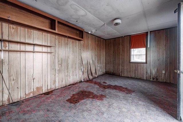 unfurnished room featuring brick floor and wooden walls