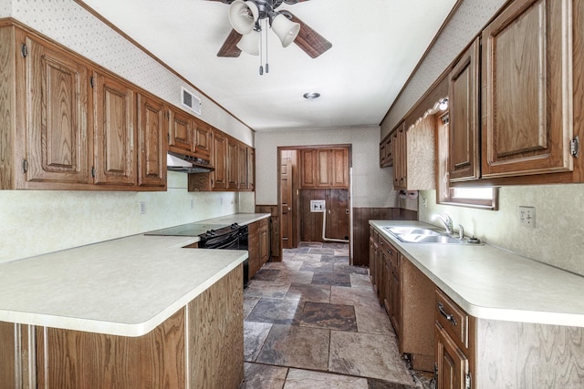 kitchen featuring visible vents, stone finish flooring, a sink, under cabinet range hood, and wallpapered walls