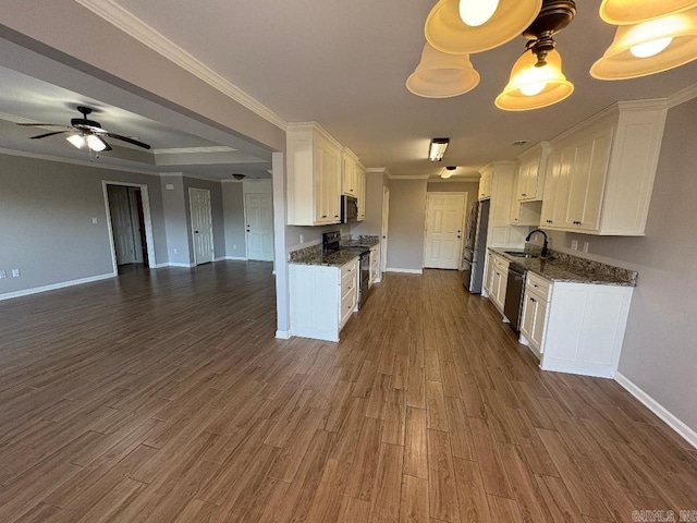 kitchen with a sink, white cabinets, open floor plan, appliances with stainless steel finishes, and dark wood-style floors