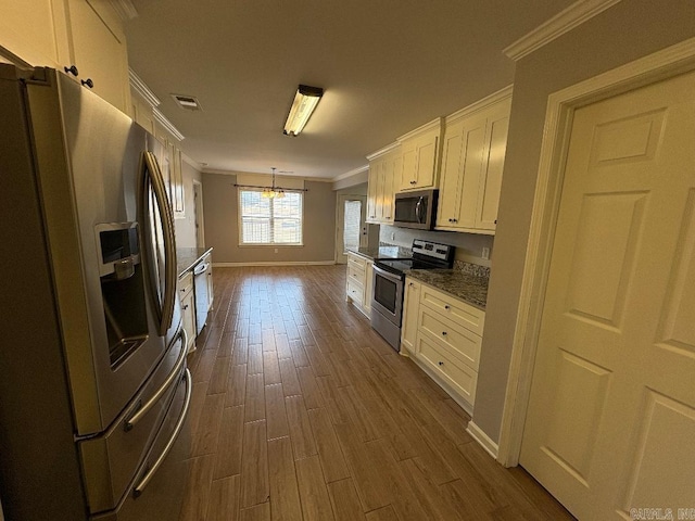 kitchen with stainless steel appliances, visible vents, ornamental molding, and white cabinetry