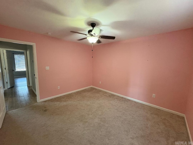 carpeted empty room featuring ceiling fan and baseboards