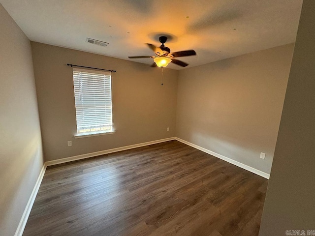 unfurnished room featuring baseboards, visible vents, ceiling fan, and dark wood-type flooring