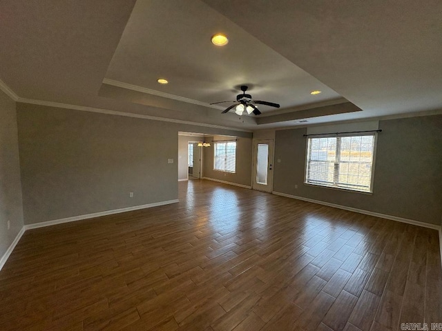 empty room with dark wood-style floors, a tray ceiling, and plenty of natural light