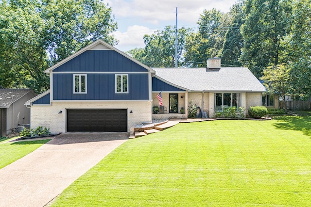 split level home with concrete driveway, a chimney, an attached garage, a front lawn, and brick siding