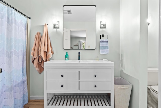 bathroom featuring baseboards, toilet, a shower with curtain, wood finished floors, and vanity