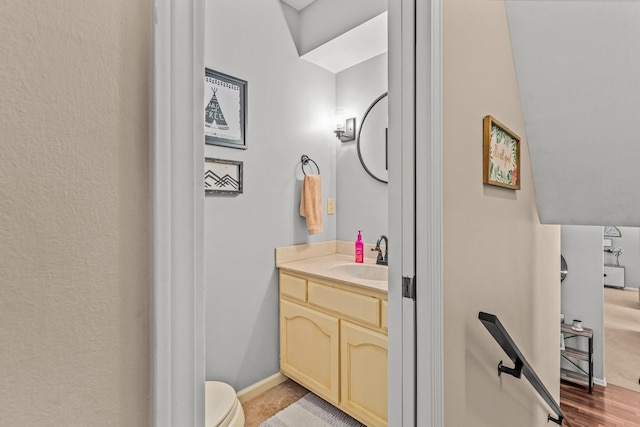 half bathroom featuring toilet, vanity, and baseboards