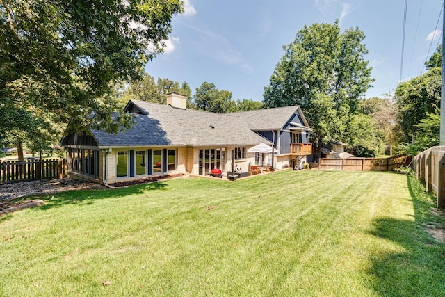 back of property featuring a yard, a shingled roof, a chimney, and brick siding