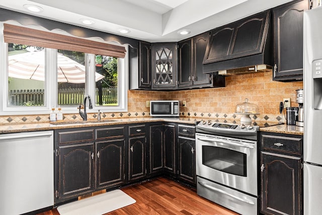 kitchen featuring dark wood-style flooring, a sink, appliances with stainless steel finishes, custom exhaust hood, and tasteful backsplash