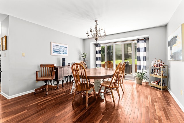 dining area with baseboards, an inviting chandelier, and wood finished floors