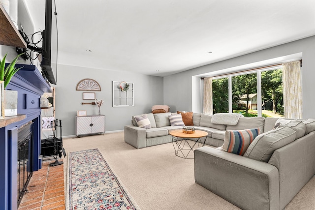 living room with a glass covered fireplace, light carpet, and baseboards