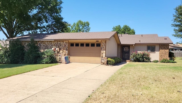 ranch-style home featuring a front yard, stone siding, an attached garage, and concrete driveway