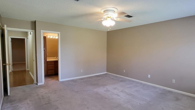 unfurnished bedroom with carpet floors, visible vents, a textured ceiling, ensuite bath, and baseboards