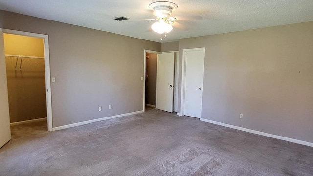 unfurnished bedroom with carpet, visible vents, baseboards, and a textured ceiling