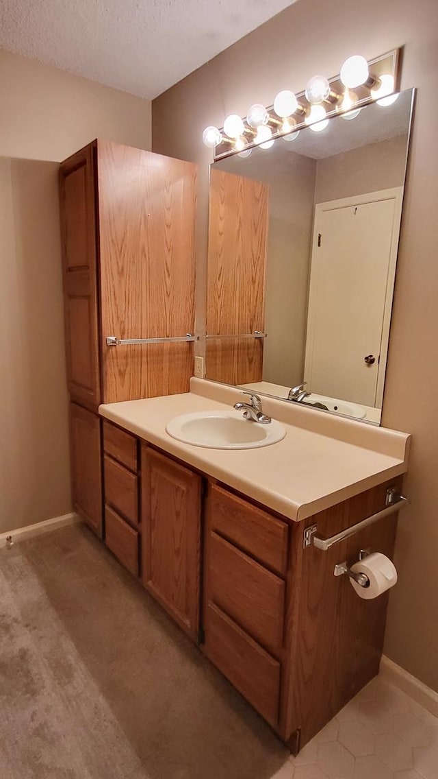 bathroom with a textured ceiling, vanity, and baseboards