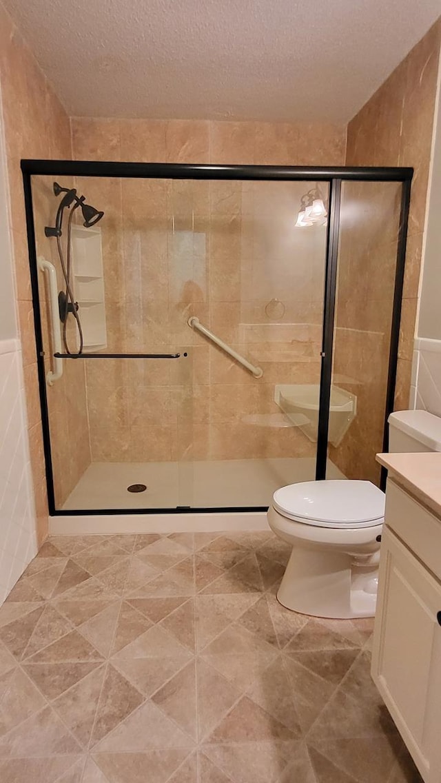 full bathroom with a textured ceiling, a stall shower, vanity, and toilet