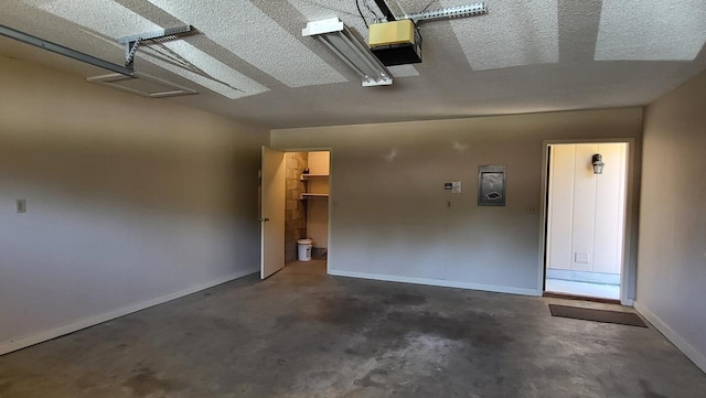 garage featuring baseboards, electric panel, and a garage door opener