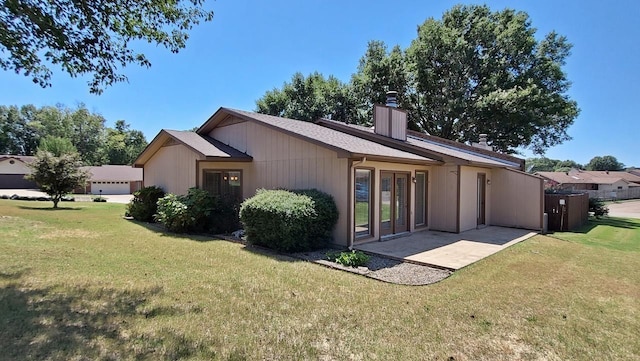 back of property featuring a patio area, a chimney, and a yard