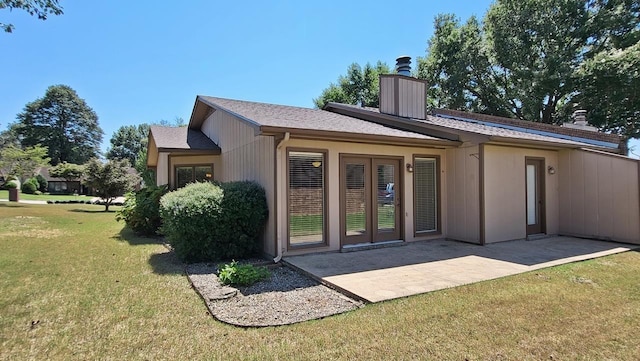 back of house with a yard, french doors, a patio, and a chimney