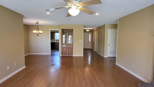 unfurnished living room with dark wood-style floors, baseboards, a textured ceiling, and ceiling fan with notable chandelier