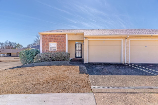 townhome / multi-family property featuring a garage, driveway, and stucco siding