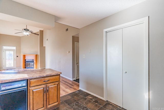 kitchen featuring visible vents, baseboards, light countertops, brown cabinets, and a tiled fireplace