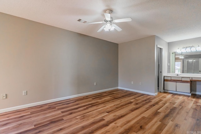 spare room with ceiling fan, a textured ceiling, baseboards, and wood finished floors